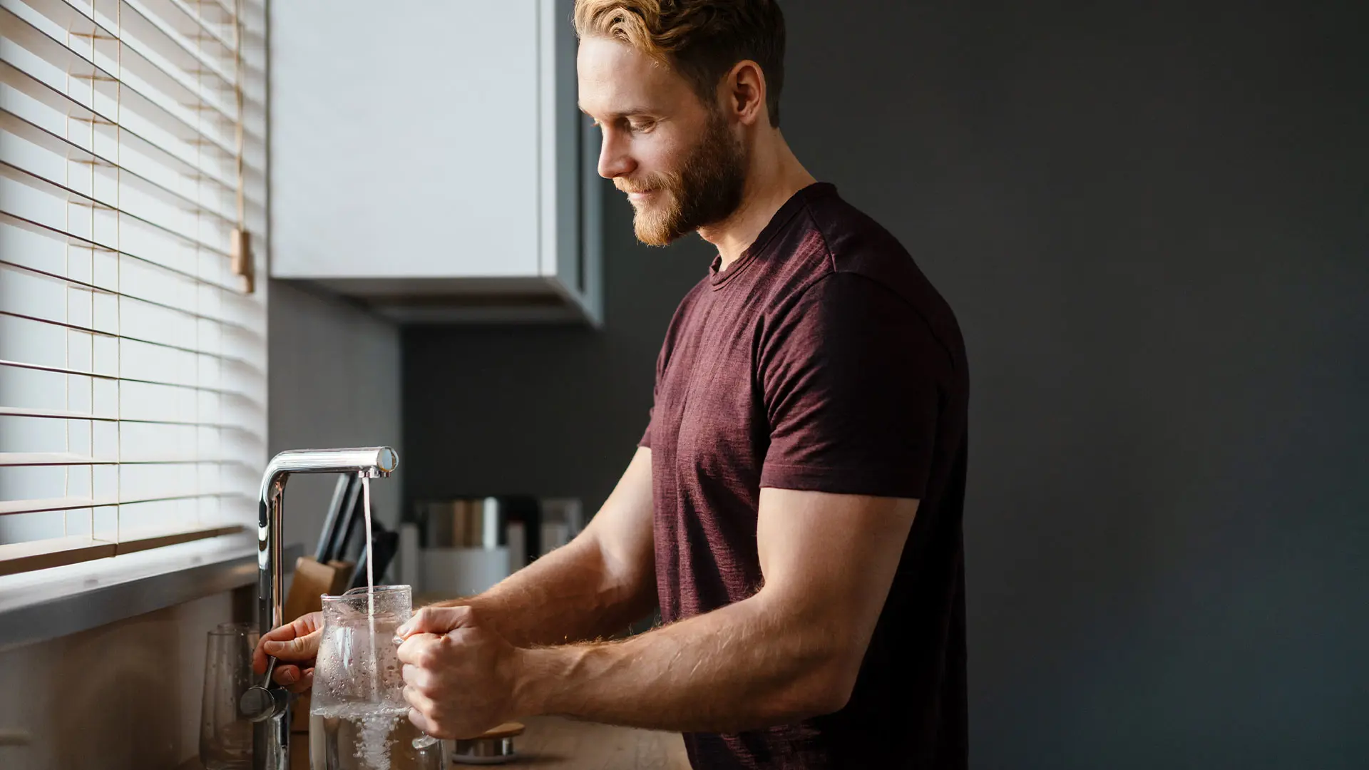 Man filling a jug with water from a tap