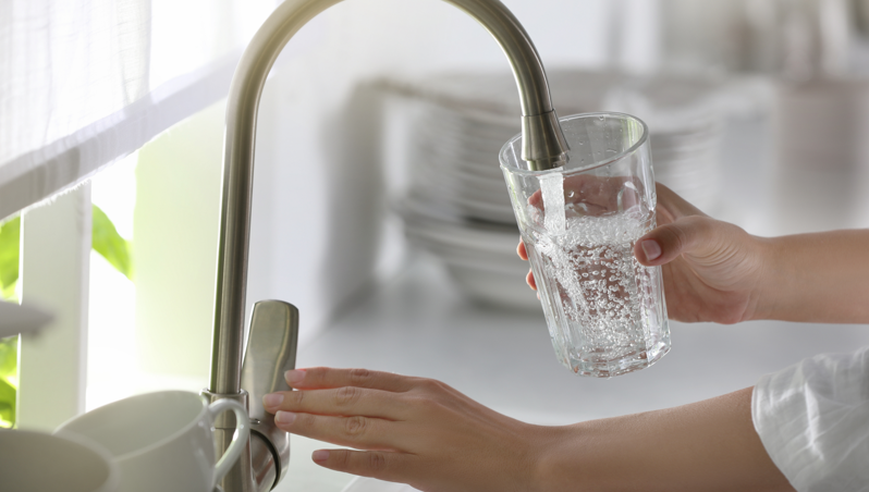 A person filling up a glass with tapwater with bubbles in the water