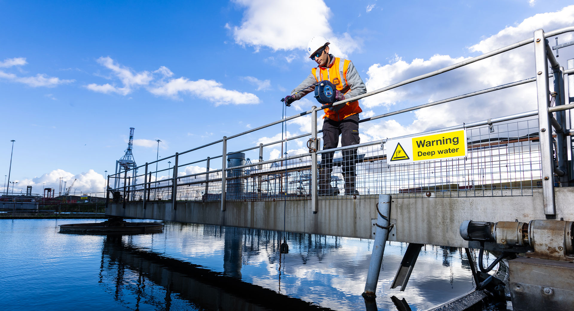 A Southern Water engineer takes a water sample from a circular clarifier at a wastewater treatment works 