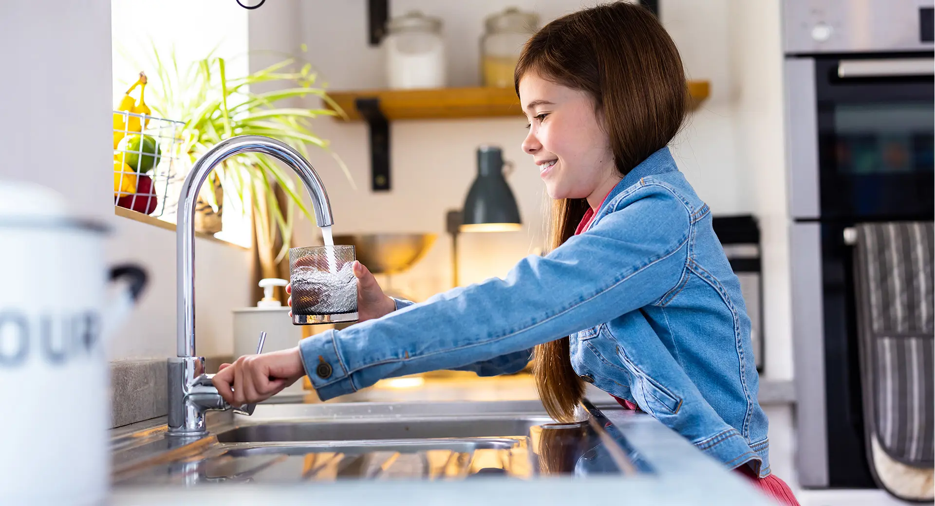 A child filling up a glass of water from a tap