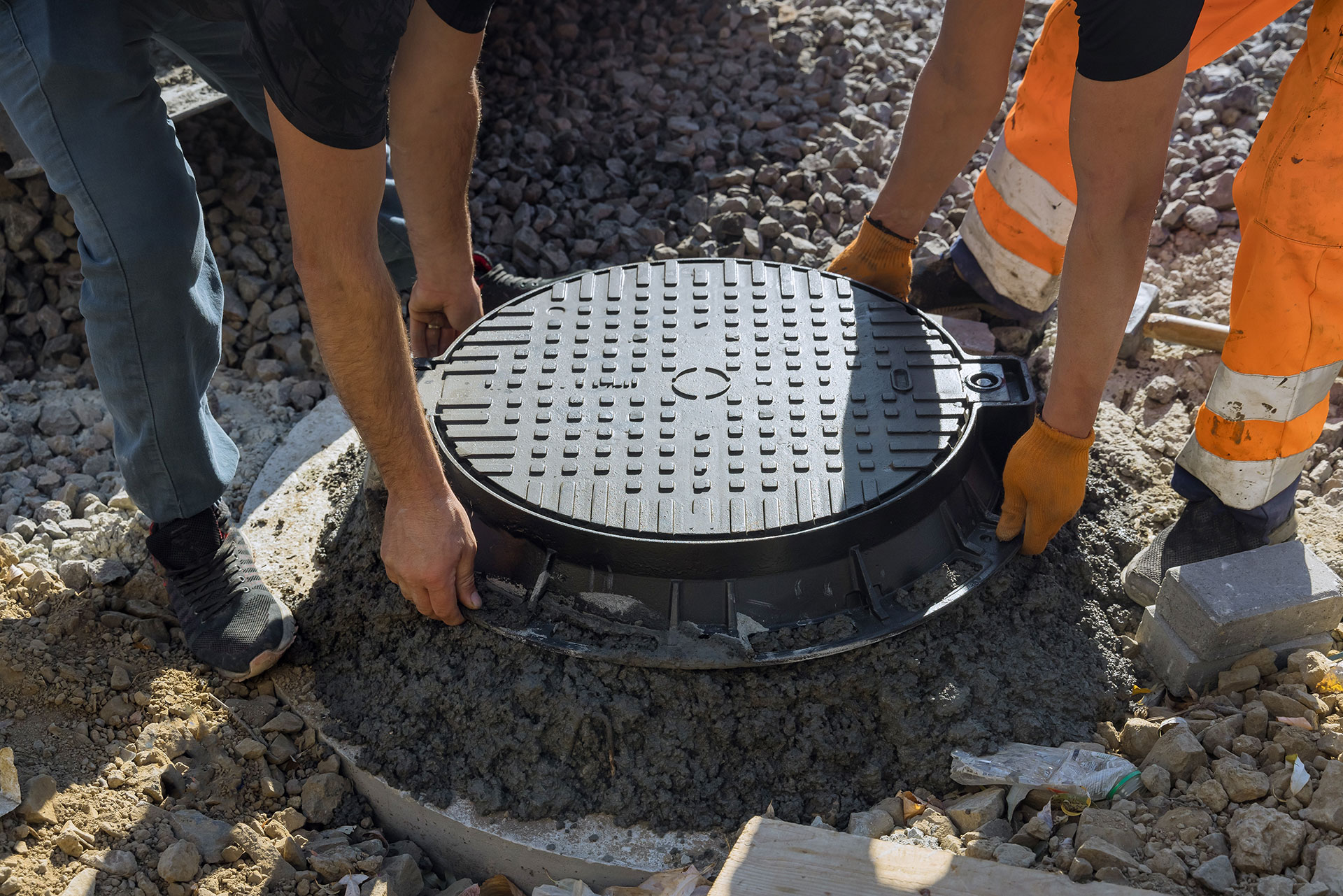 Workers removing a sewer cover
                        